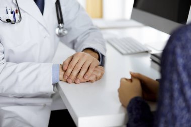 Dost canlısı kızıl sakallı doktor, kadın hastasına güvence veriyor, yakın plan. Tıp etiği ve güven kavramı, tıp teması