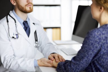 Dost canlısı kızıl sakallı doktor, kadın hastasına güvence veriyor, yakın plan. Tıp etiği ve güven kavramı, tıp teması