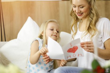 Güneşli dairede anneler günün kutlu olsun. Çocuk kızı annesini tebrik ediyor ve ona kalp çizimiyle kartpostal atıyor. Aile kavramı