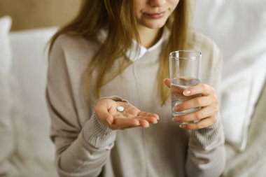 Kapalı çekim kadın ilaç almak için zaman tutuyor, baş ağrısı için tedavi, yüksek tansiyon veya kolesterol seviyesinde ağrı kesici ilaçlar. Coronavirus salgını ve kendi kendine olan konseptinde kal.