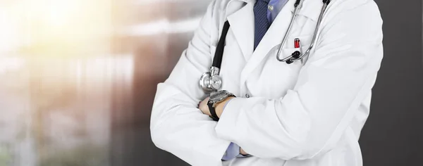 Unbekannter Arzt steht mit verschränkten Armen in sonniger Klinik. Medizinkonzept während der Coronavirus-Pandemie. Covid-2019 — Stockfoto
