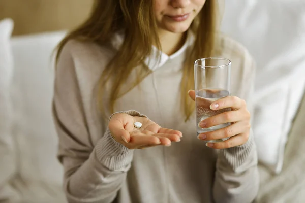 Close-up woman holding pills time to take medications, cure for headache, high blood pressure or cholesterol level remedy pain killer drugs. Stay at home concept during Coronavirus pandemic and self