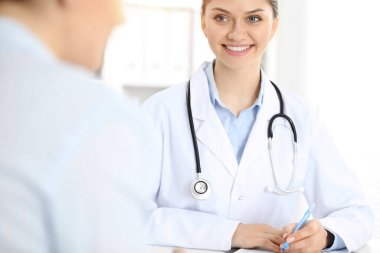 Dost canlısı gülümseyen doktor ve hasta masada oturuyor.