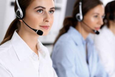Merkezi ara. Bir grup operatör iş başında. Kulaklıklı güzel iş kadınına odaklan.