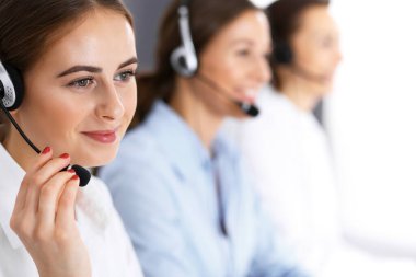 Merkezi ara. Bir grup operatör iş başında. Kulaklıklı güzel iş kadınına odaklan.