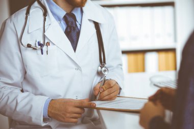 Bilinmeyen kızıl sakallı doktor ve hasta kadın güneşli klinikte otururken sağlık muayenesini tartışıyorlar. Tıp konsepti