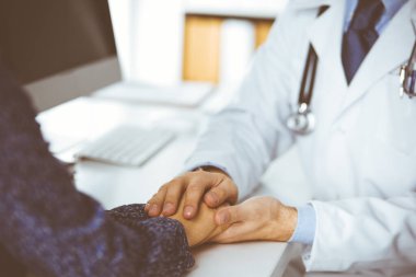 Dost canlısı kızıl sakallı doktor, kadın hastasına güvence veriyor, yakın plan. Tıp etiği ve güven kavramı, tıp teması