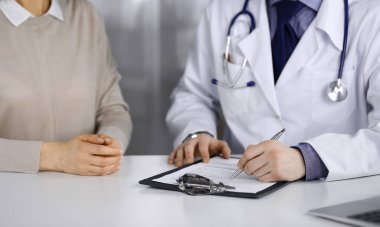 Bilinmeyen erkek doktor ve hasta kadın klinikte oturup dosya kullanırken bir şey tartışıyorlar. Hastanedeki en iyi sağlık hizmeti, ilaç, salgın durdurma.
