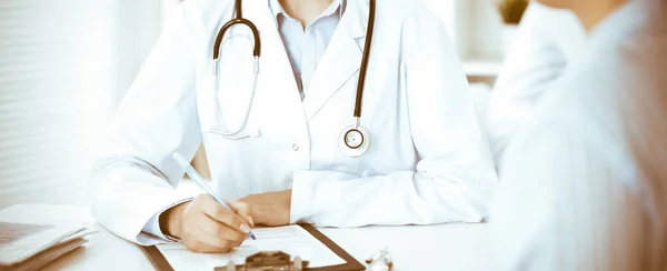 Mulher-médica desconhecida e paciente sentada à mesa. Muito boa notícia e conceito de serviço médico de alto nível — Fotografia de Stock