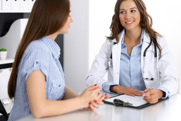 Médico y paciente feliz hablando mientras está sentado en el escritorio. El médico o terapeuta discute el estilo de vida saludable. Concepto de atención de salud, medicina y servicio al paciente — Foto de Stock