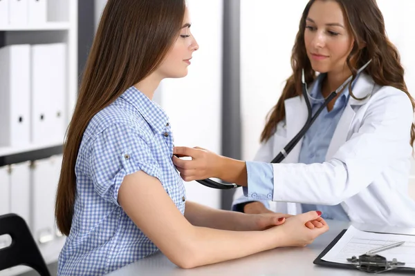 Doctor with a stethoscope in the hand examining her female patient. Health care, cardiology and medicine concepts Royalty Free Stock Images