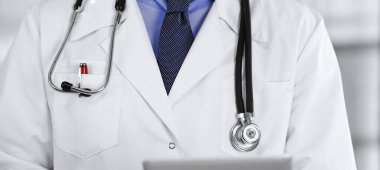 Klinikte dururken elinde tablet bilgisayar tutan kimliği belirsiz bir erkek doktor. Coronavirüs salgını sırasında ilaç kavramı