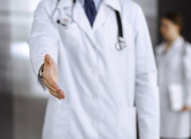 Bilinmeyen bir adam-doktor ayakta duruyor ve modern klinikte yardım eli uzatıyor. Kadın meslektaşının doktor geçmişinde acelesi var. Tıp konsepti