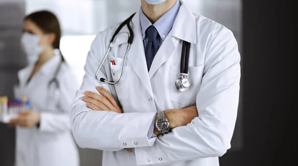 Sconosciuto medico maschio in maschera protettiva in piedi con le braccia incrociate in clinica. Concetto di medicina durante la pandemia di Coronavirus. Covid 2019 — Foto Stock