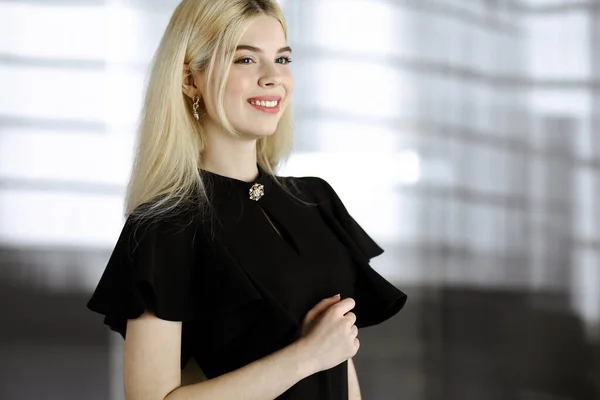 Die junge blonde Geschäftsfrau oder Studentin in Schwarz steht gerade und posiert vor der Kamera. Lebensstil und vielfältiges Personenkonzept — Stockfoto