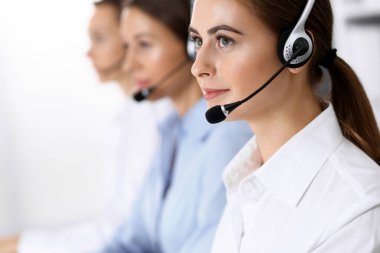 Merkezi ara. Bir grup operatör iş başında. Kulaklıklı güzel iş kadınına odaklan.