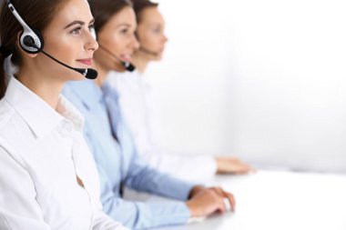 Merkezi ara. Bir grup operatör iş başında. Kulaklıklı güzel iş kadınına odaklan.