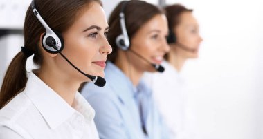 Merkezi ara. Bir grup operatör iş başında. Kulaklıklı güzel iş kadınına odaklan.