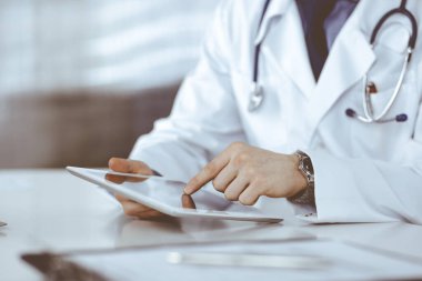 Bilinmeyen erkek doktor klinikteki tablet bilgisayarla yakın planda çalışıyor. İşteki genç doktor. Mükemmel sağlık hizmeti, tıp konsepti