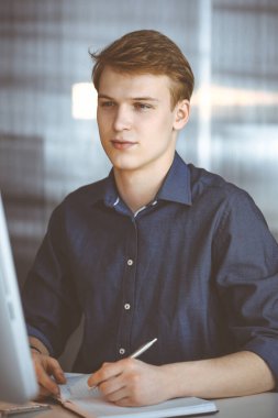 Bilgisayarla çalışan genç sarışın iş adamı. Girişim işi, başarı için çok çalışmak ve zamanın dışında çalışmak demektir.