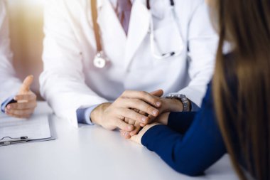 Bilinmeyen erkek-doktor, kadın hastasına güvence veriyor, yakın plan. İki doktor kadınlara danışmanlık yapıyor ve tavsiyelerde bulunuyor. Tıbbi ahlak ve güven kavramları. Tıpta empati