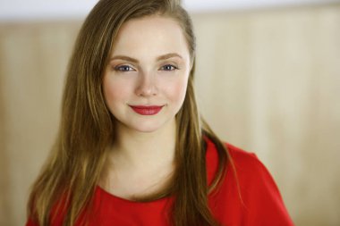 Zeki, kendinden emin, gülümseyen, Avrupalı bir kadının kollarını kavuşturup evinde dikilirken çekilmiş bir fotoğrafı. Çekici genç kız öğrenci serbest çalışan, kırmızı giyinmiş, kameraya bakıyor.