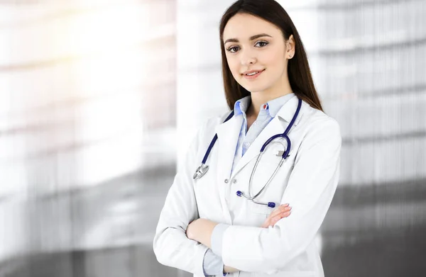 Sorridente giovane donna-medico è in piedi in clinica soleggiata al chiuso — Foto Stock