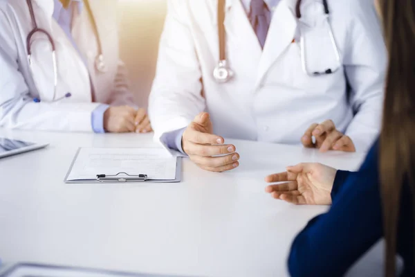Paciente mulher e dois médicos estão discutindo algo enquanto sentado na mesa na clínica moderna. Serviço médico perfeito, conceito de medicina — Fotografia de Stock