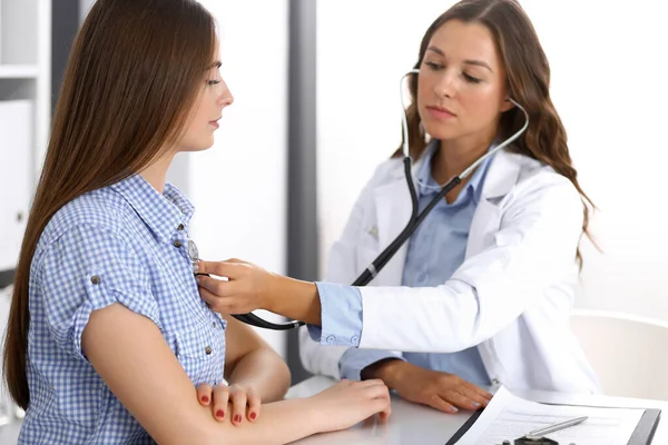 Doctor with a stethoscope in the hand examining her female patient. Health care, cardiology and medicine concepts Stock Image