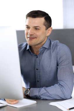 Modern ofiste bilgisayarla çalışan bir iş adamı. İş yerindeki erkek girişimcinin ya da şirket müdürünün vesikalığı. İş konsepti