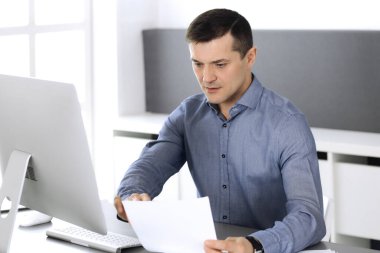 Modern ofiste bilgisayarla çalışan bir iş adamı. İş yerindeki erkek girişimcinin ya da şirket müdürünün vesikalığı. İş konsepti