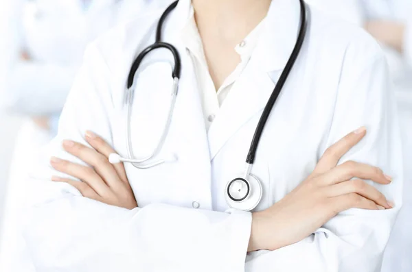 Onbekende vrouw-dokter die recht staat met gekruiste armen in de kliniek, close-up. Medisch team klaar om coronavirus pandemie te stoppen. Geneesmiddelenconcept — Stockfoto