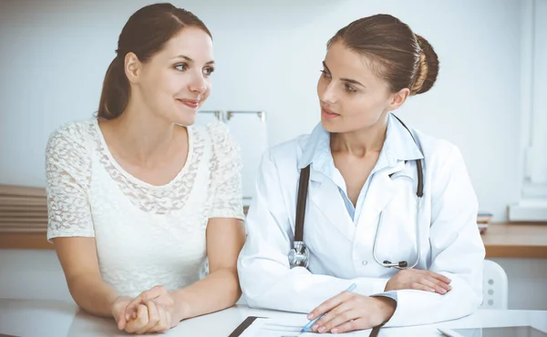 Doctor and patient having a pleasure talk while sitting at the desk at hospital office. Healthcare and medicine concept — Stock Photo, Image