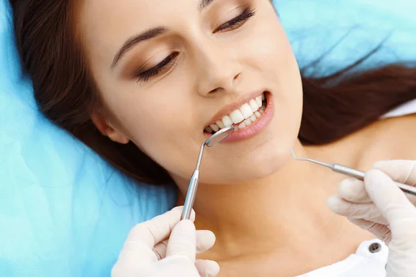 若い女性は歯医者さんが歯で働いている間、口腔検査中に開いた口で歯の椅子に座って健康的なストレート白い歯を持つ美しい女性 — ストック写真