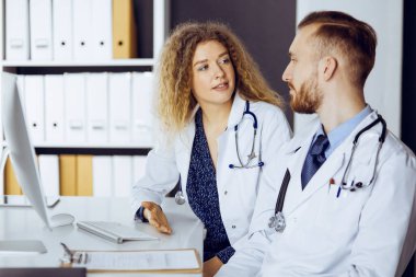 Kızıl sakallı doktor ve bayan meslektaşı klinikte çalışırken güncel hastalık terapisini tartışıyorlar. Tıpta takım çalışması