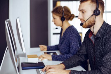 Günümüz güneşli ofisinde otururken, kulaklıkla konuşan kızıl sakallı bir iş adamı. Çağrı merkezinde çeşitli insanlar grubu