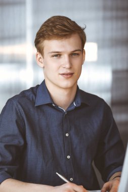 Bilgisayarla çalışan genç sarışın iş adamı. Girişim işi, başarı için çok çalışmak ve zamanın dışında çalışmak demektir.