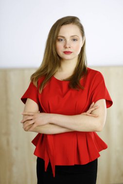 Zeki, kendinden emin, gülümseyen, Avrupalı bir kadının kollarını kavuşturup evinde dikilirken çekilmiş bir fotoğrafı. Çekici genç kız öğrenci serbest çalışan, kırmızı giyinmiş, kameraya bakıyor.