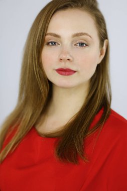 Zeki, kendinden emin, gülümseyen, Avrupalı bir kadının kollarını kavuşturup evinde dikilirken çekilmiş bir fotoğrafı. Çekici genç kız öğrenci serbest çalışan, kırmızı giyinmiş, kameraya bakıyor.