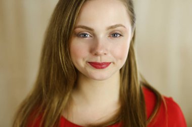 Zeki, kendinden emin, gülümseyen, Avrupalı bir kadının kollarını kavuşturup evinde dikilirken çekilmiş bir fotoğrafı. Çekici genç kız öğrenci serbest çalışan, kırmızı giyinmiş, kameraya bakıyor.