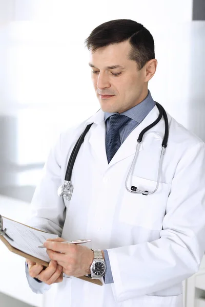 Dokter man met behulp van klembord voor het vullen van medicatie geschiedenis verslagen. Perfecte medische dienst in de kliniek. Artsen op het werk in het ziekenhuis. Begrippen geneeskunde en gezondheidszorg — Stockfoto