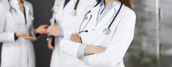 Okänd ung kvinnlig läkare står med armarna korsade på kliniken. Medicinskt koncept under Coronavirus pandemi — Stockfoto