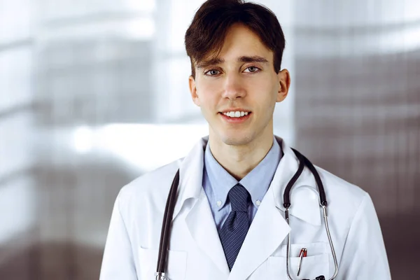 在现代诊所，友好的年轻男医生与剪贴板站在一起。医学概念 — 图库照片