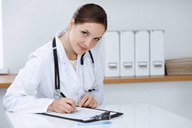 Kadın doktor klinikte oturuyor ve çalışıyor. Kadın doktor portresi. Tıp konsepti