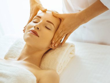 Güneşli spa merkezinde yüz masajından hoşlanan güzel bir kadın. Tıpta rahatlatıcı tedavi kavramı