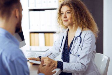 Kadın doktor ve erkek hasta klinikte otururken sağlık muayenesini tartışıyorlar. Mükemmel tıbbi hizmet ve tıp konsepti