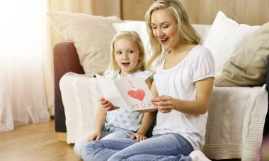 Güneşli dairede anneler günün kutlu olsun. Çocuk kızı annesini tebrik ediyor ve ona kalp çizimiyle kartpostal atıyor. Aile kavramı