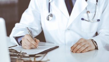 Bilinmeyen erkek doktor, klinikteki ilaç geçmişi kayıtlarıyla birlikte yakın planda oturuyor. İşteki genç doktor. Mükemmel sağlık hizmeti, tıp konsepti