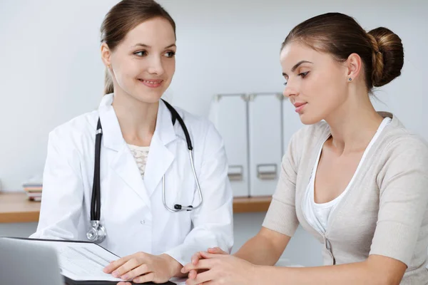 Dokter en patiënt zitten en bespreken gezondheidsonderzoek resultaten in kliniek kantoor. Gezondheidszorg, geneeskunde en goede nieuwsconcepten — Stockfoto