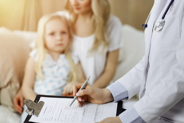 Dokter en patiënt. Kinderarts die klembord gebruikt terwijl ze het kleine meisje onderzoekt met haar moeder thuis. Ziek en ongelukkig kind bij medisch onderzoek — Stockfoto